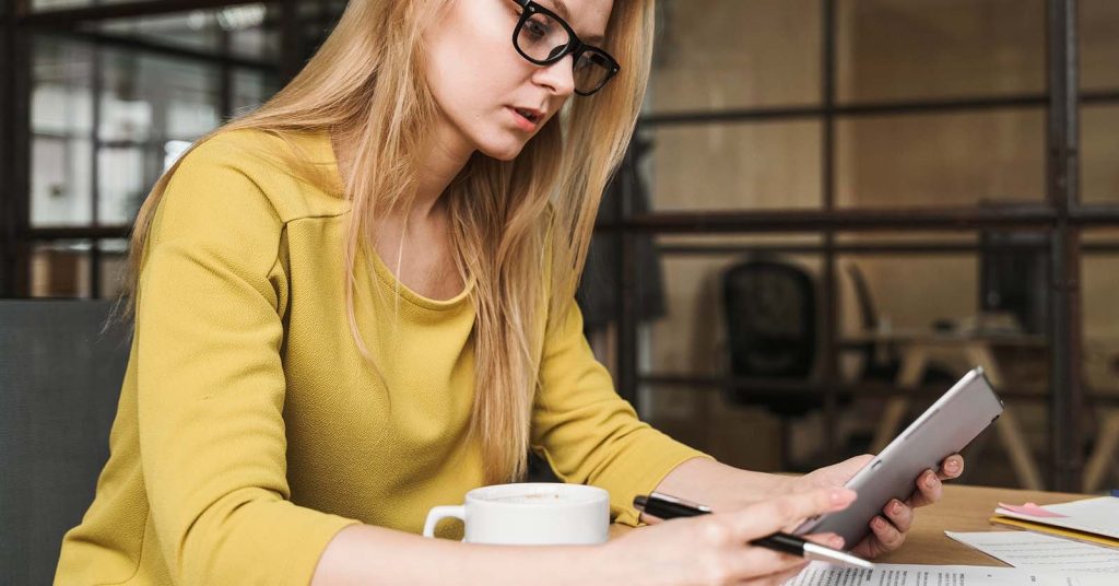 Woman comparing life insurance quotes on a tablet beside policy documents