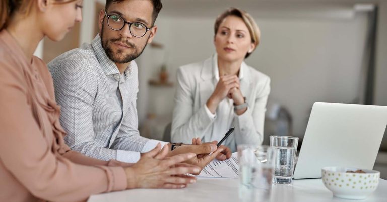 Couple discussing documents with an adviser at a table