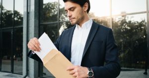 Man opening a letter outside an office building