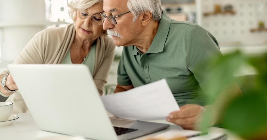 Senior couple reviewing documents on a laptop at home