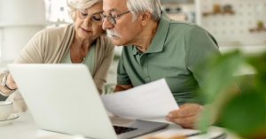 Senior couple reviewing documents on a laptop at home