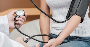 Medical examiner measuring an applicant's blood pressure during a life insurance medical exam