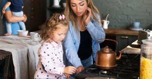 Mother preparing food with her daughter while a father holds a baby in the kitchen
