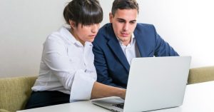 Two professionals reviewing information on a laptop